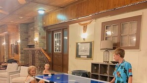 A room with a ping pong table, a sofa, and a staircase.