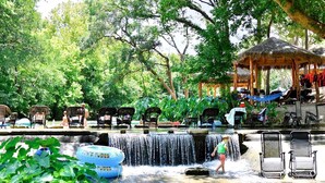 A water feature with chairs and a gazebo in a lush, green setting.