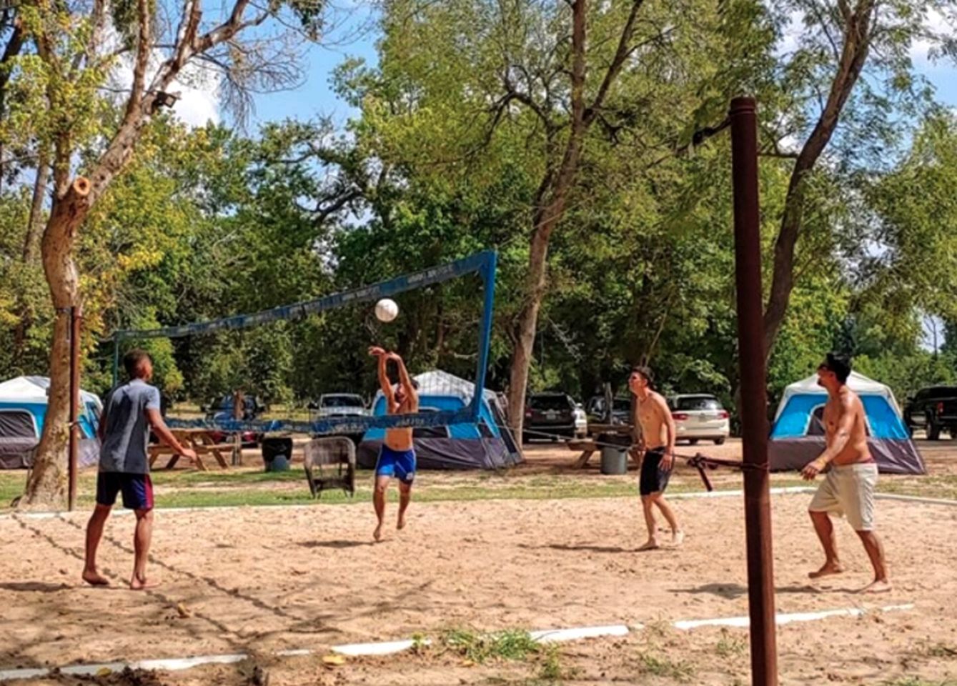 Un terrain de volleyball de plage, avec des tentes en arrière-plan.