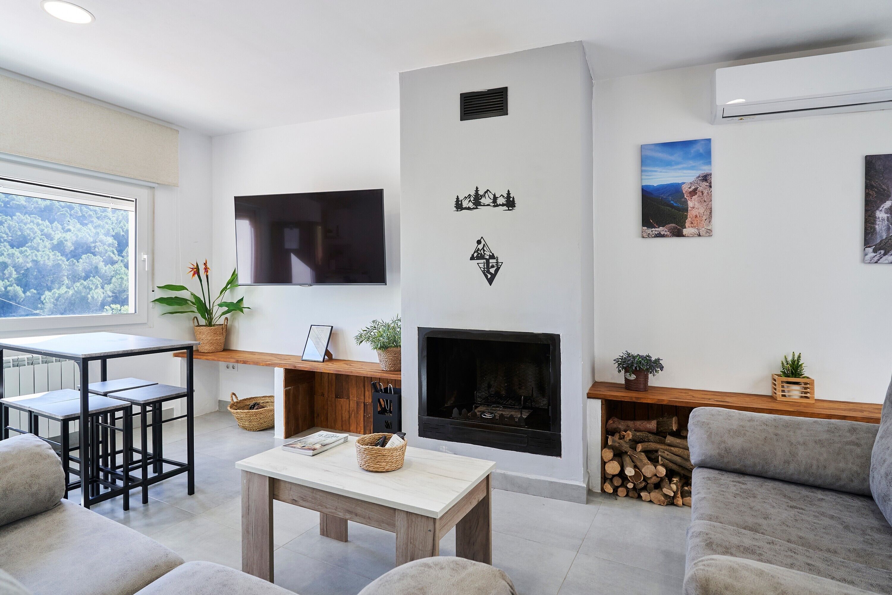 Una sala de estar con chimenea, un televisor de pantalla plana, un sofá, una mesa de centro y un comedor con sillas.
