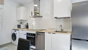 A modern kitchen with stainless steel appliances, white cabinetry, and a built-in dishwasher.