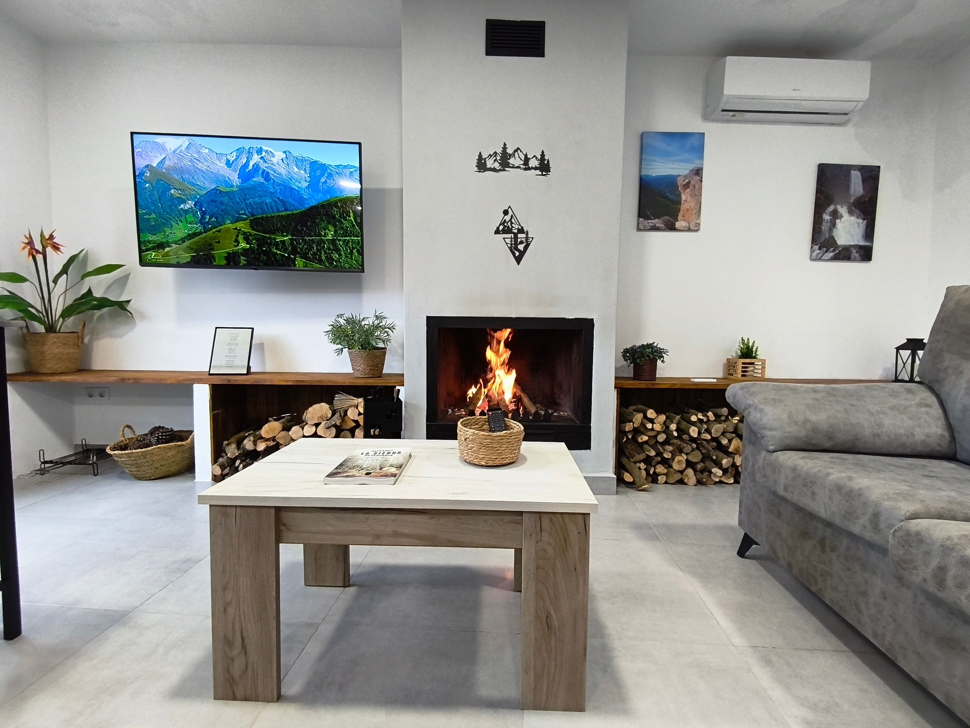 Een woonkamer met een open haard, een televisie en een bank.