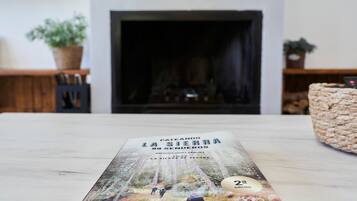 Een boek met de titel 'Pateando la Sierra 99 Senderos' op een tafel, met een open haard op de achtergrond.