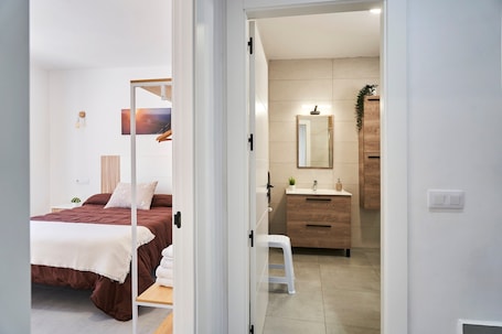 A bedroom with a bed, a nightstand, and a bedside table. There is a bathroom with a sink, mirror, and wooden cabinet.. Chalet 'Alojamiento Rural El Lentisco' with Mountain Views, Wi-Fi & Air Conditioning