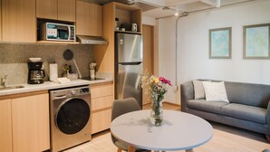 A compact kitchen with modern appliances, a dining area with a round table, and a grey sofa. - Modern 1BR in Juárez with fast WiFi, great natural light, a comfortable king bed, a fully equipped kitchen, and a luxury bathroom. Perfect for couples or solo travelers seeking comfort, style, and a prime location in Mexico City. (Cuauhtémoc)