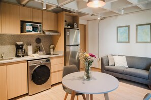 A compact kitchen with modern appliances, a dining area with a round table, and a grey sofa. - Modern 1BR in Juárez with fast WiFi, great natural light, a comfortable king bed, a fully equipped kitchen, and a luxury bathroom. Perfect for couples or solo travelers seeking comfort, style, and a prime location in Mexico City. (Cuauhtémoc)