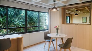 A modern room with a large window, a round table with chairs, and a vase with flowers. - Modern 1BR in Juárez with fast WiFi, great natural light, a comfortable king bed, a fully equipped kitchen, and a luxury bathroom. Perfect for couples or solo travelers seeking comfort, style, and a prime location in Mexico City. (Cuauhtémoc)