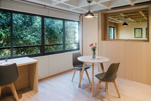 A modern room with a large window, a round table with chairs, and a vase with flowers. - Modern 1BR in Juárez with fast WiFi, great natural light, a comfortable king bed, a fully equipped kitchen, and a luxury bathroom. Perfect for couples or solo travelers seeking comfort, style, and a prime location in Mexico City. (Cuauhtémoc)