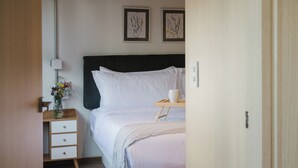 Ein ordentlich eingerichtetes Schlafzimmer mit Bett, Nachttisch, Lampe und Bildern an der Wand.