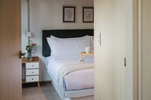 Ein ordentlich eingerichtetes Schlafzimmer mit Bett, Nachttisch, Lampe und Bildern an der Wand.