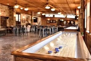 A bar area with a shuffleboard table, wooden ceiling, and bar stools. - Cabaña Son's Rio Cibolo Waterfront Cabin, San Antonio, Texas (Marion)