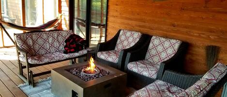 A cozy porch with wicker furniture, a fire pit, and a 'WELCOME TO OUR PORCH' sign.