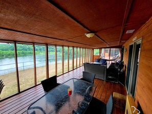 A wooden deck with a glass table and chairs, overlooking a river. - Arkansas River Paradise: Cabin with Large Deck Overlooking Breathtaking Views (Calico Rock)