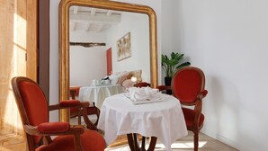 A dining area with a round table, two chairs, a large mirror, and a potted plant. - Charming Gîte in Périgord for 2 to 6 Guests (Saint-Martin-de-Gurson)