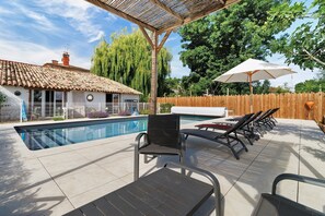 A swimming pool with lounge chairs and a pergola.