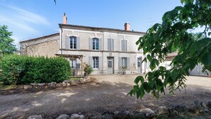 A two-story building with a stone facade, multiple windows, and a gravel driveway. - Charming Gîte in Périgord for 2 to 6 Guests (Saint-Martin-de-Gurson)