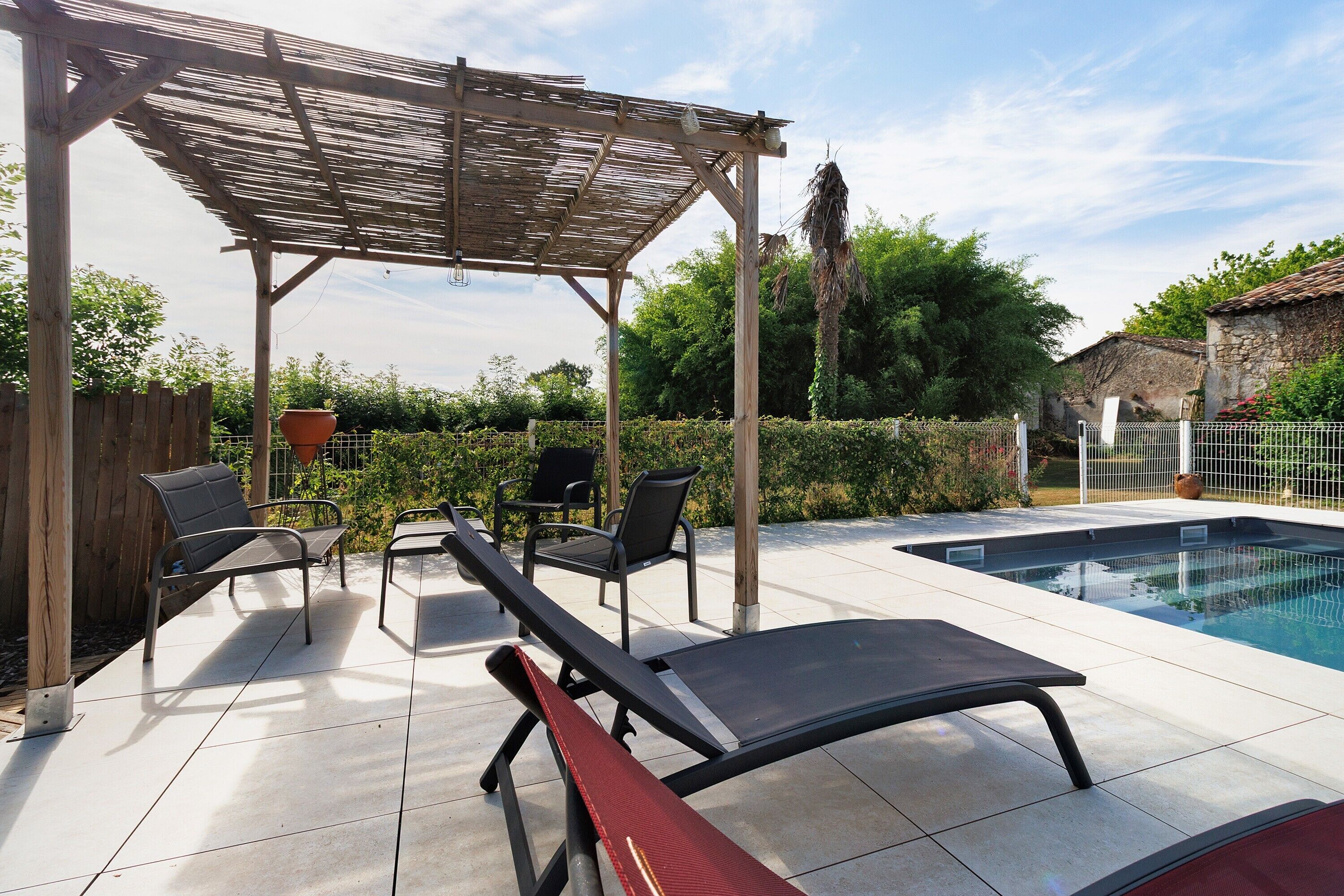 Ett takförsett utomhusområde med en pool, solstolar och en pergola.