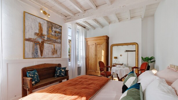 A bedroom with a large bed, a wooden bench, a wardrobe, a mirror, and a painting on the wall. - Charming Gîte in Périgord for 2 to 6 Guests (Saint-Martin-de-Gurson)
