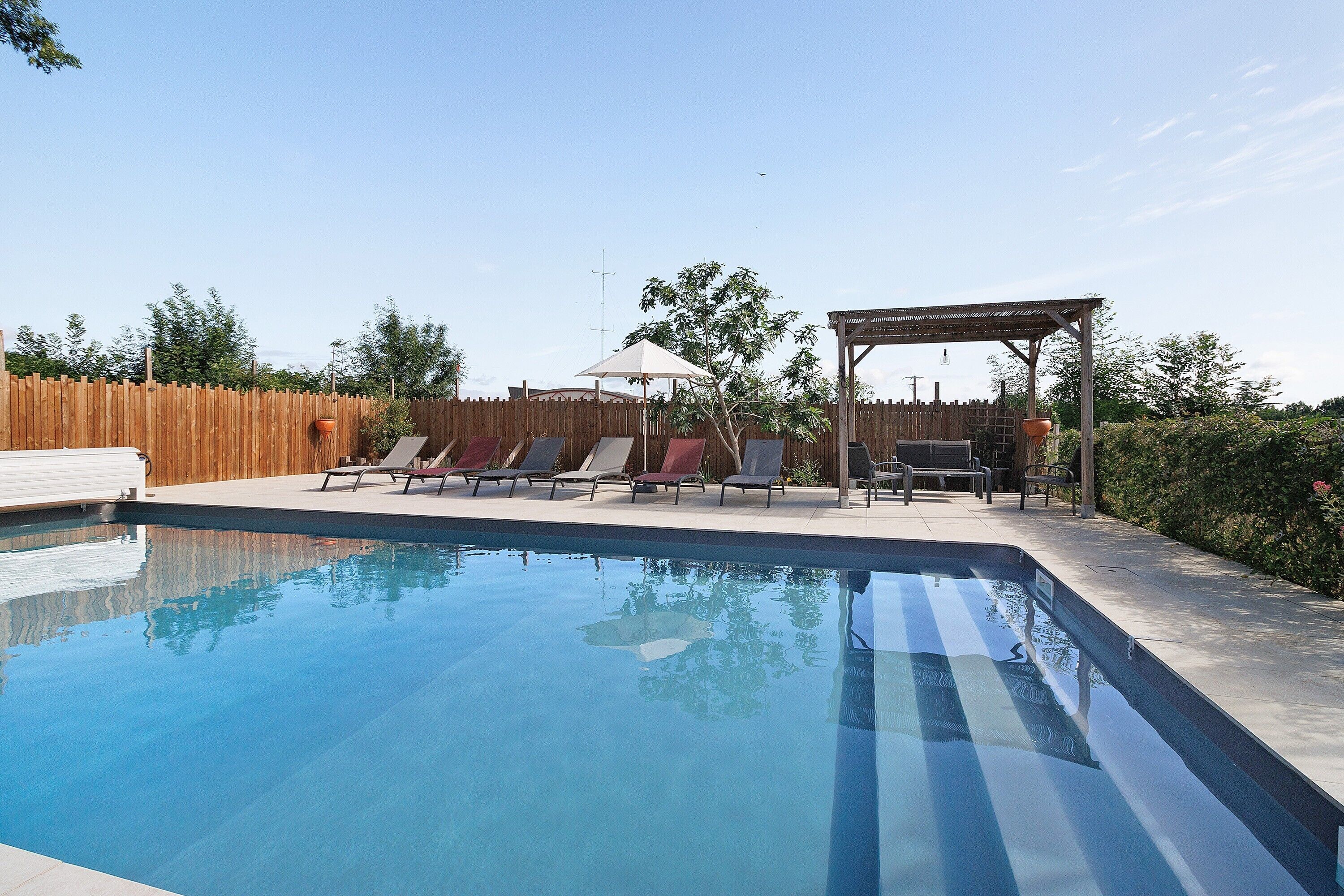 A swimming pool with lounge chairs and a pergola.