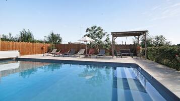A swimming pool with lounge chairs and a pergola.