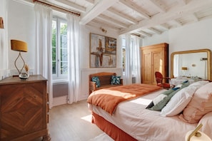 Quarto com cama, cómoda de madeira e um espelho grande.