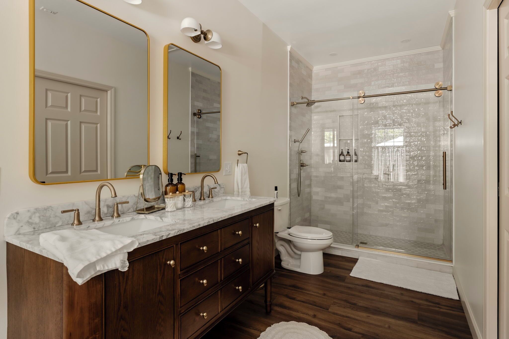Une salle de bain avec un meuble-lavabo en marbre, un grand miroir, des toilettes et une douche à parois de verre.