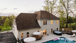 A house with a swimming pool, outdoor seating, and a hot tub.