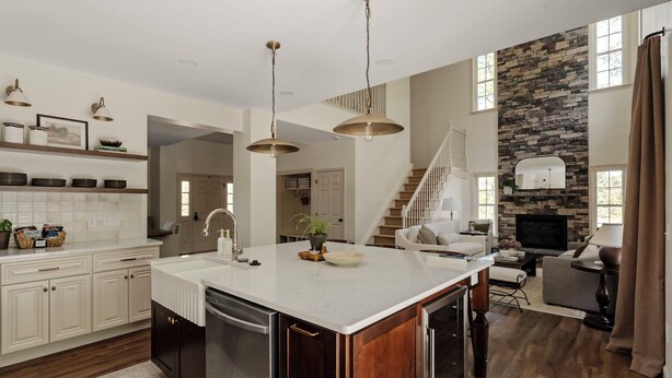 A spacious kitchen with a large island, wooden cabinets, and pendant lighting.