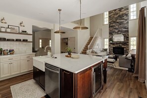 A spacious kitchen with a large island, wooden cabinets, and pendant lighting. - Fallen Pines Villa - Pool, Hot Tub, Pickleball (Elysburg)