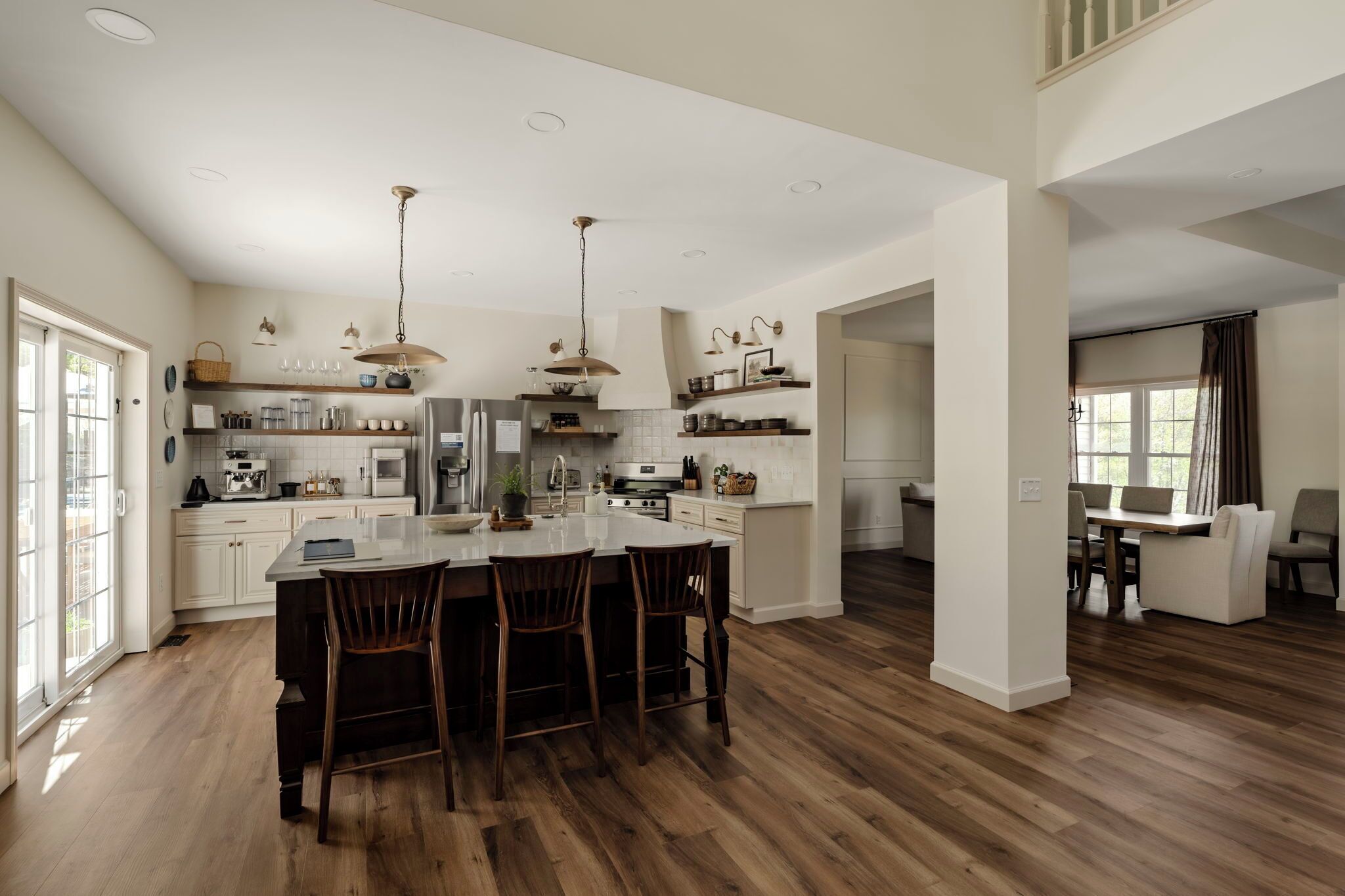A spacious kitchen with a central island, wooden flooring, and pendant lighting.