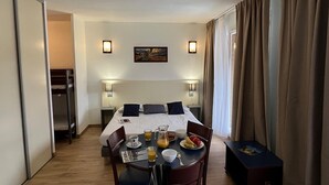 A hotel room with a bed, bedside lamps, a dining table with breakfast, and a view of the outdoors. - Attractive Studio in Bolquere (Bolquere)