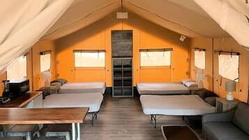 A tented accommodation with a central sleeping area, a dining table, and a sofa.