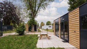 A modern outdoor area with a picnic table, a pathway, and a building with large windows.