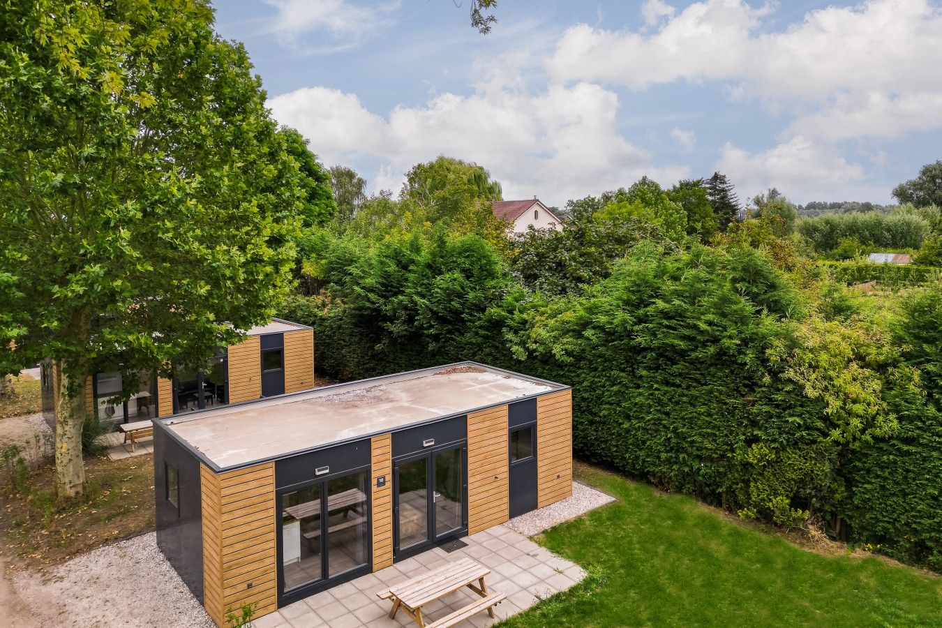 A modern outdoor kitchen area with a built-in grill, seating, and a view of the surrounding garden.