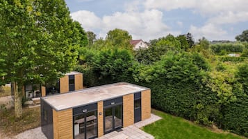 A modern outdoor kitchen area with a built-in grill, seating, and a view of the surrounding garden.