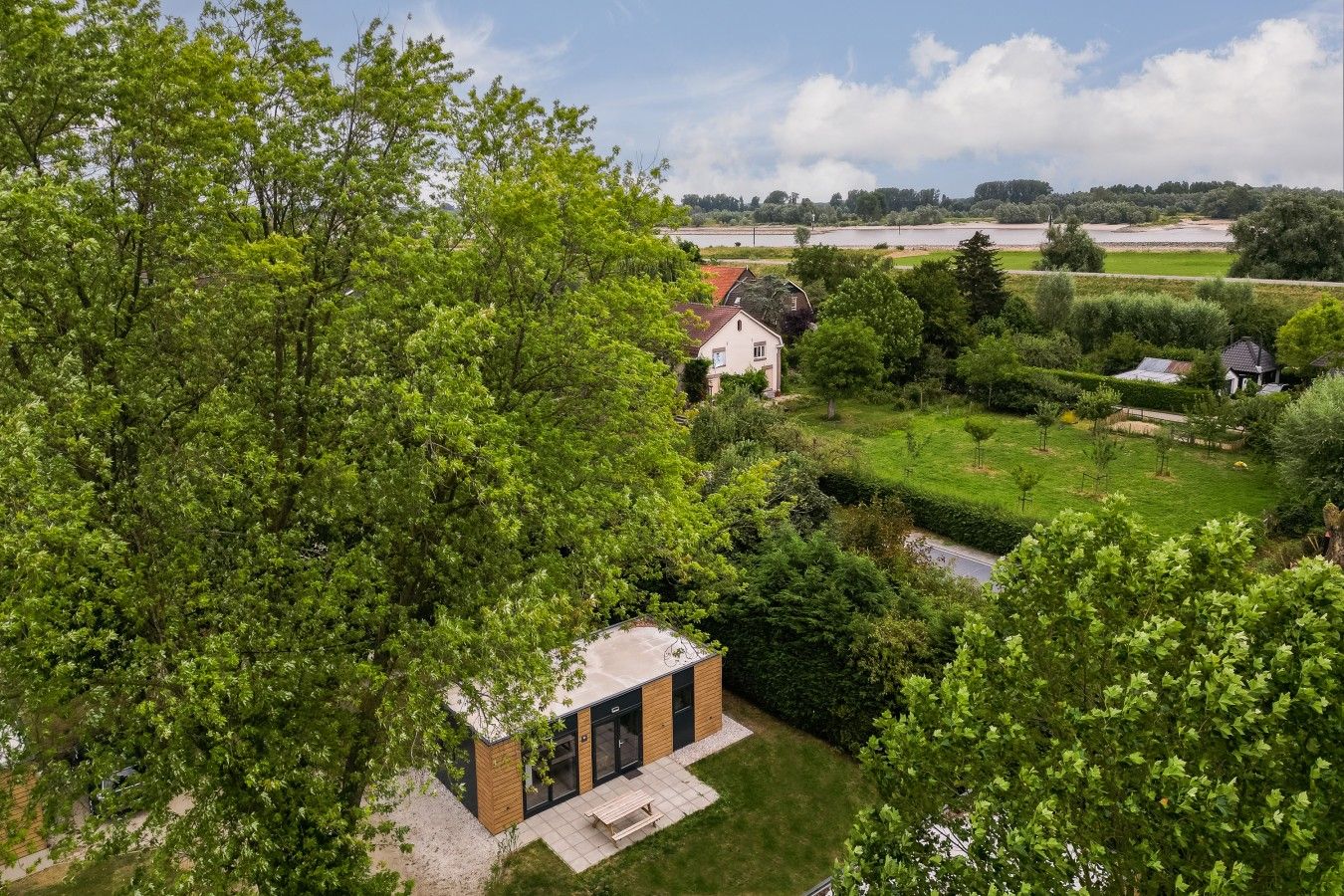 A residential area with a small house, a paved pathway, and a grassy field.