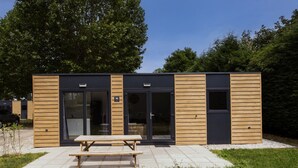 A modern building with a wooden exterior, large glass doors, and a picnic table in front.