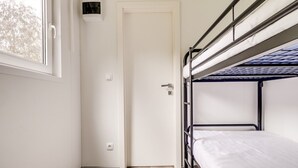 A bunk bed room with a door, a window, and a thermostat on the wall.