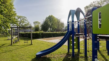 Een speeltuin met een glijbaan, klimconstructies en een picknicktafel.