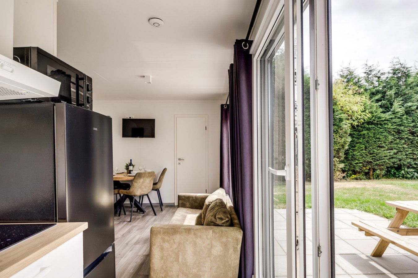 Een moderne keuken met een inbouwoven en een eethoek met een tafel en stoelen.