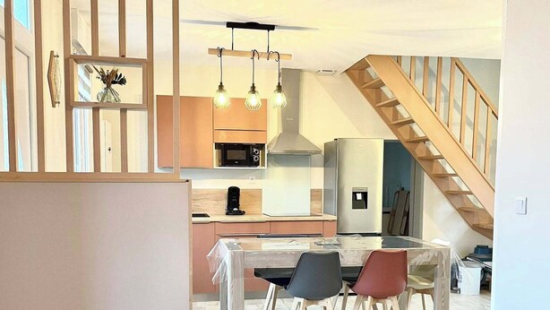 Un espace de vie moderne comprenant un coin repas, une cuisine et un escalier.