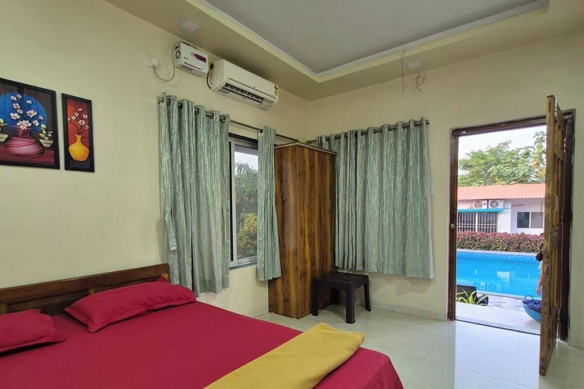 A hotel room with a bed, air conditioning unit, curtains, and a view of the outside.