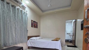 Um quarto com uma cama, uma mesa pequena, um espelho e um ar condicionado.