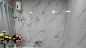 Uma casa de banho com uma banheira de mármore, chuveiro e sanita.