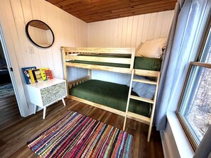 A bunk bed room with a white console table, a colorful striped rug, and a window with curtains. - Charming Lakefront Cabin with Hot Tub and Beach Access near Traverse City, Michigan (Traverse City)