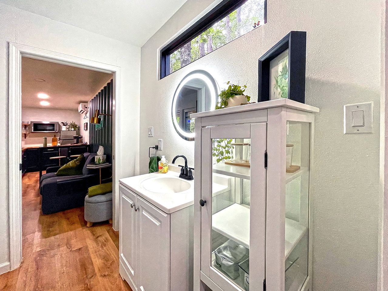A modern bathroom with a sink, mirror, and glass cabinet.