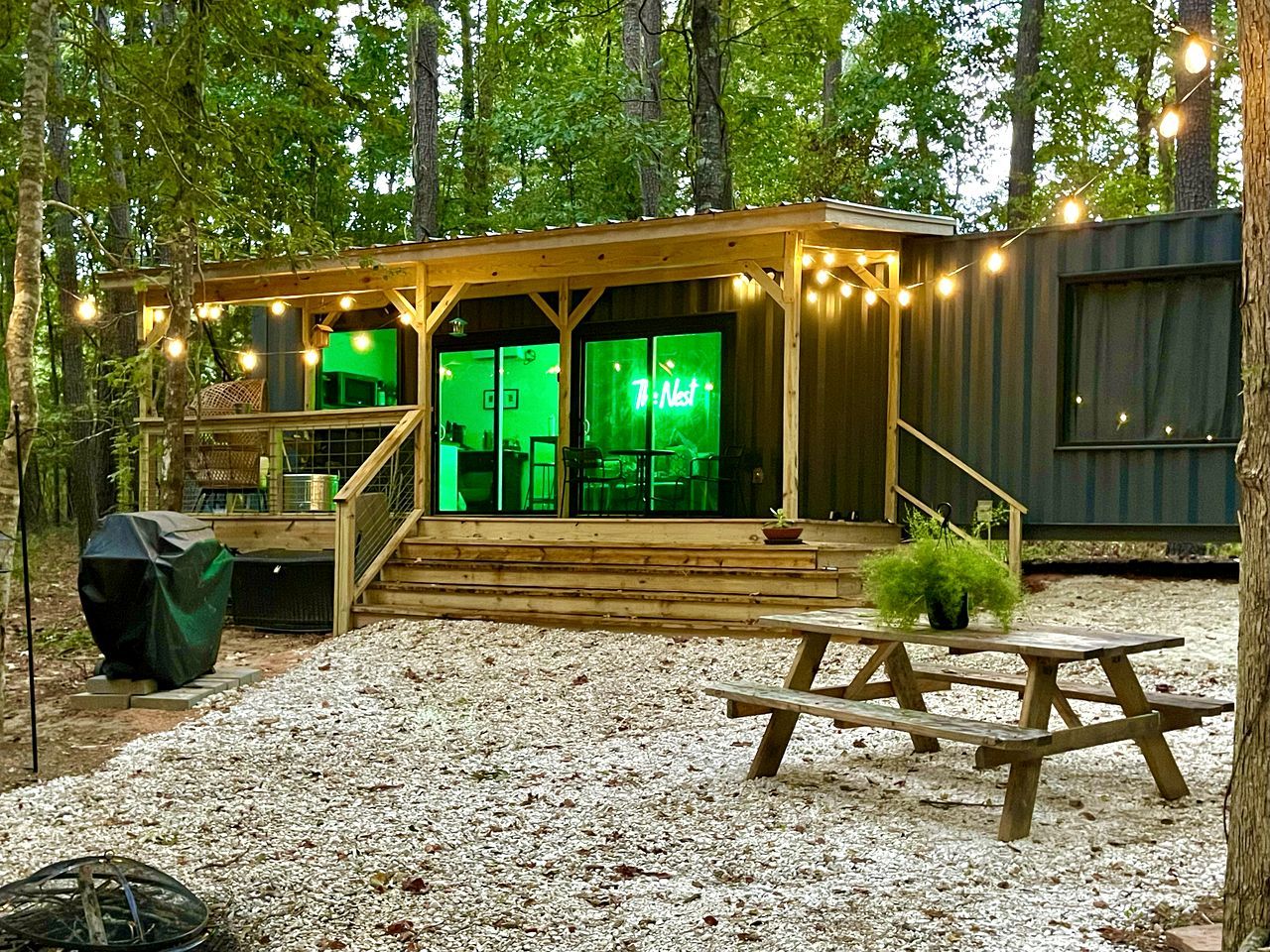 A wooden cabin with a covered deck, outdoor seating, and string lights.