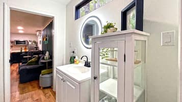 A modern bathroom with a sink, mirror, and glass cabinet.