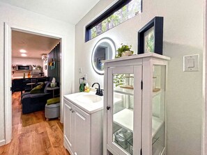 A modern bathroom with a sink, mirror, and glass cabinet. - Minimalist Luxury: Fully Equipped Modern Container, Hidden Getaway near Lake Livingston, TX (Polk County)