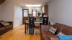Uma sala de estar moderna com um sofá de couro marrom, uma mesa de jantar com cadeiras e uma área de cozinha com armários de madeira e uma janela.